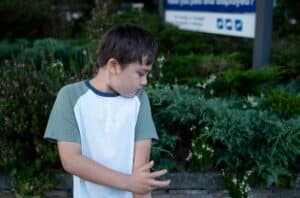 boy standing in the park scratching his arm,Child itchy skin from insect bite in the garden,