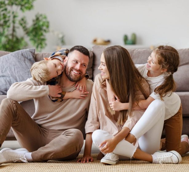 happy family mother father and children at home on floor next to the sofa