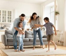 Happy family playing funny game having fun together with little son and daughter in modern living room. Young dad and mother with adorable cute children doing exercises, enjoying weekend at home.